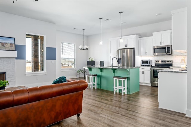 living room featuring a notable chandelier, a brick fireplace, dark wood-type flooring, and visible vents