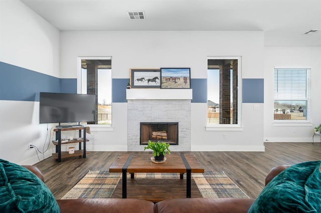 living area featuring visible vents, a fireplace, baseboards, and wood finished floors