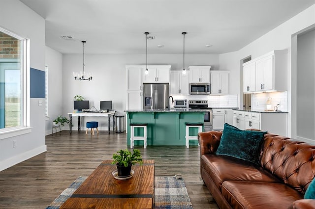 living room featuring baseboards, dark wood-style floors, visible vents, and a chandelier