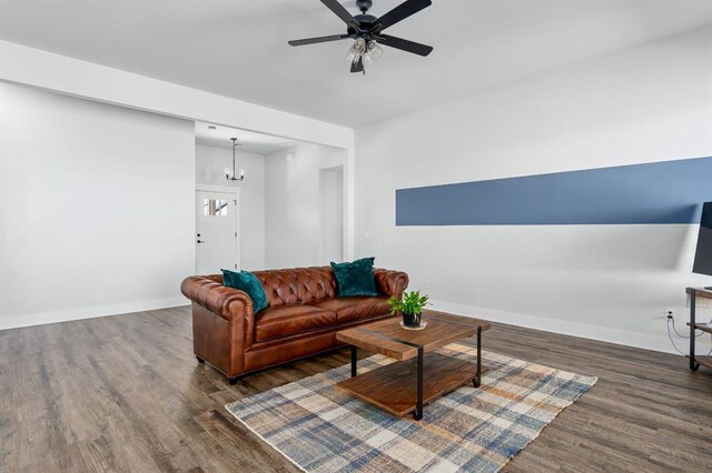 living room with ceiling fan with notable chandelier, wood finished floors, and baseboards