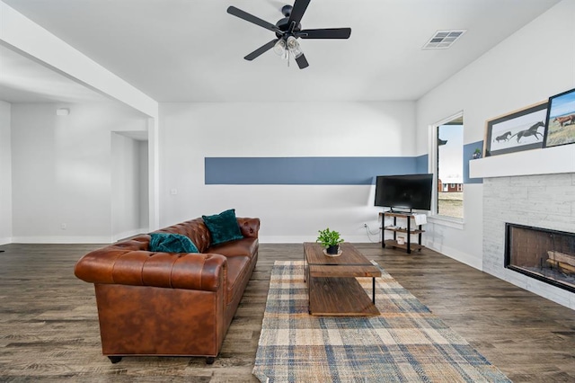 living room with visible vents, baseboards, wood finished floors, and a fireplace