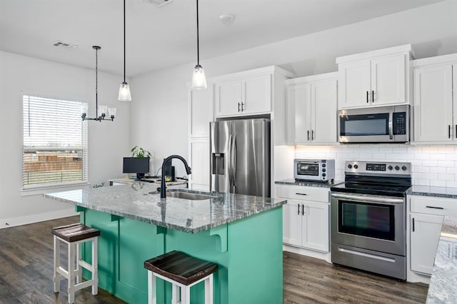 kitchen featuring light stone counters, visible vents, a sink, decorative backsplash, and appliances with stainless steel finishes