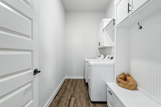 washroom featuring washer and clothes dryer, cabinet space, baseboards, and dark wood-style flooring