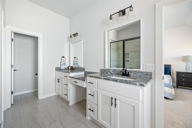 full bath with a shower stall, two vanities, baseboards, and a sink