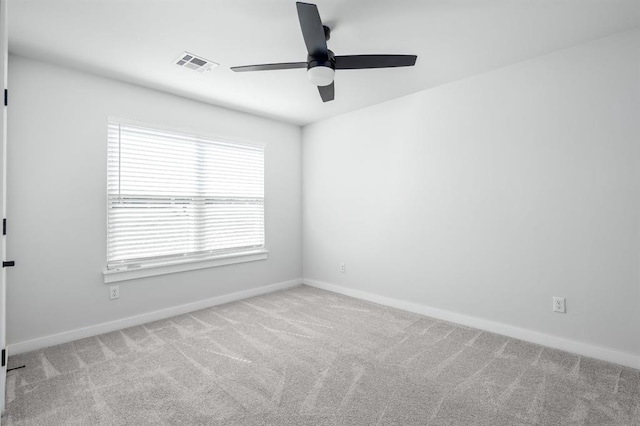 carpeted spare room featuring baseboards, visible vents, and ceiling fan