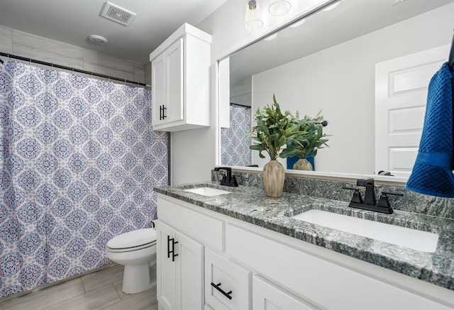 bathroom with double vanity, toilet, visible vents, and a sink