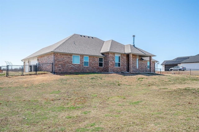 back of property featuring a yard, brick siding, roof with shingles, and fence