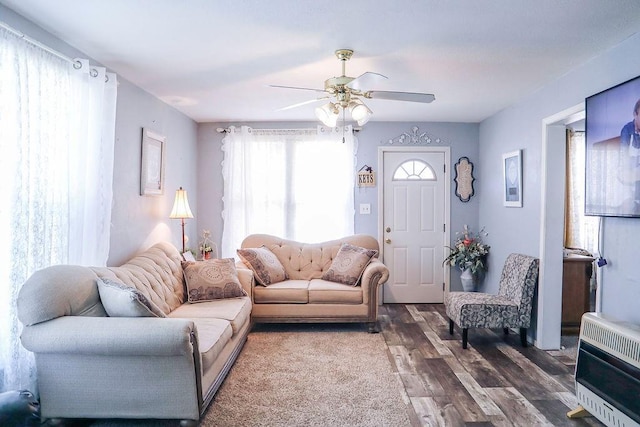 living area featuring heating unit, ceiling fan, and wood finished floors