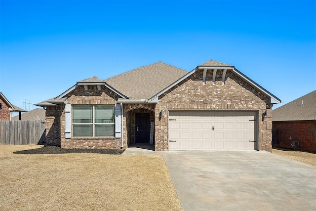 view of front of property featuring brick siding, fence, roof with shingles, a garage, and driveway