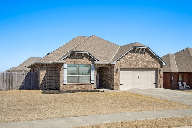 view of front facade featuring driveway, fence, an attached garage, a shingled roof, and brick siding