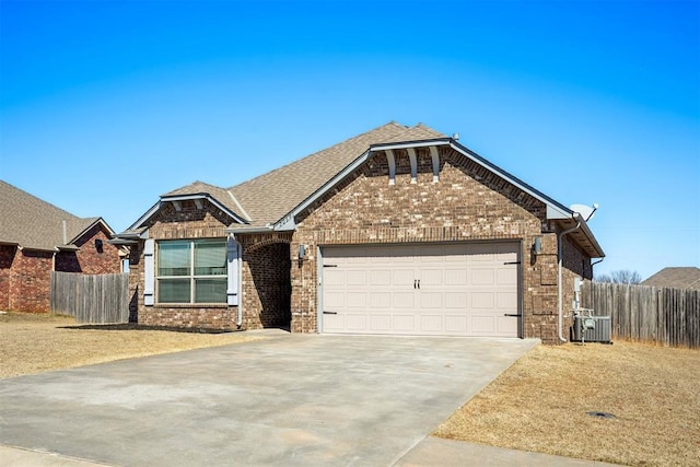 view of front of house with brick siding, concrete driveway, a garage, and fence