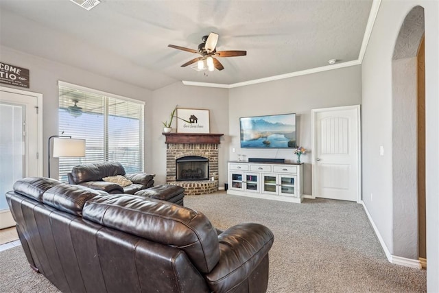 living area featuring a ceiling fan, baseboards, carpet, a fireplace, and ornamental molding