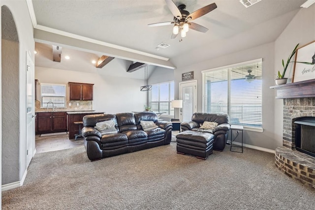 living area with visible vents, a ceiling fan, a fireplace, baseboards, and light colored carpet