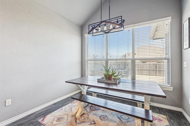 dining space featuring vaulted ceiling, wood finished floors, and baseboards