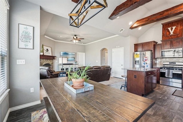 dining area featuring visible vents, lofted ceiling with beams, arched walkways, a fireplace, and baseboards