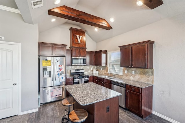 kitchen featuring visible vents, a sink, lofted ceiling with beams, a kitchen island, and appliances with stainless steel finishes