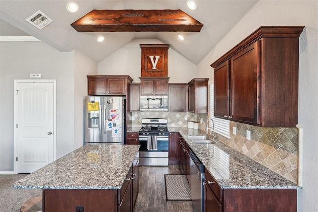 kitchen with visible vents, a center island, vaulted ceiling with beams, stainless steel appliances, and a sink