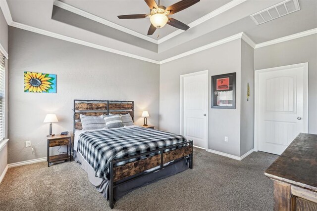 bedroom featuring visible vents, a tray ceiling, carpet flooring, crown molding, and baseboards