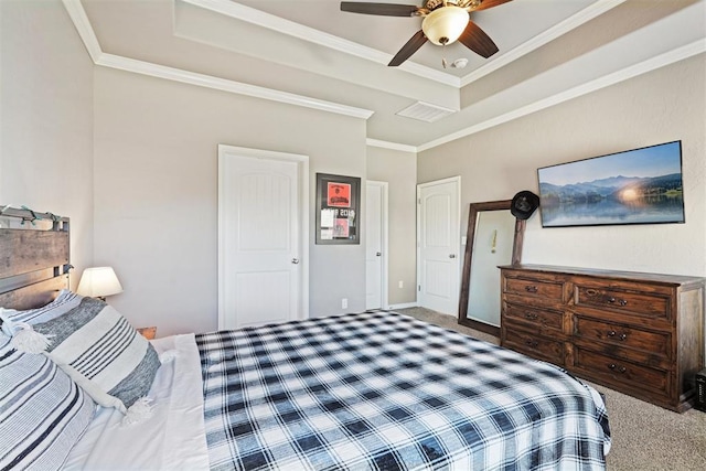 carpeted bedroom featuring a ceiling fan, a tray ceiling, crown molding, and baseboards