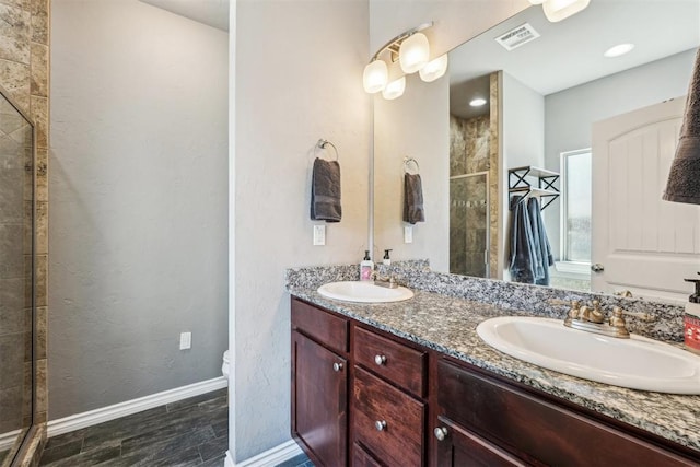 full bath with double vanity, baseboards, a stall shower, and a sink