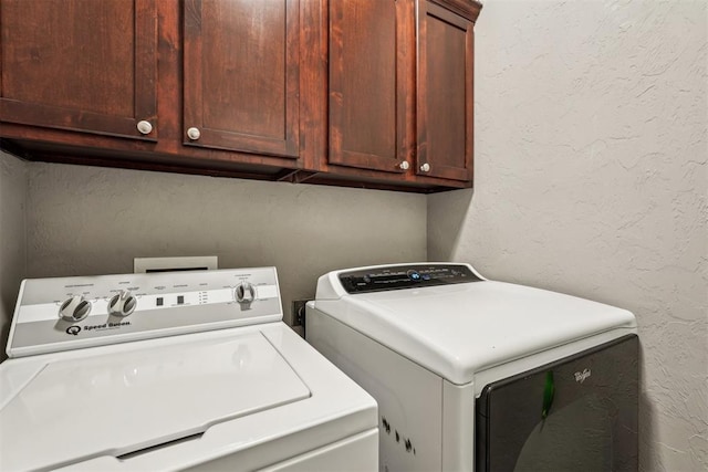 laundry room with washing machine and clothes dryer, cabinet space, and a textured wall