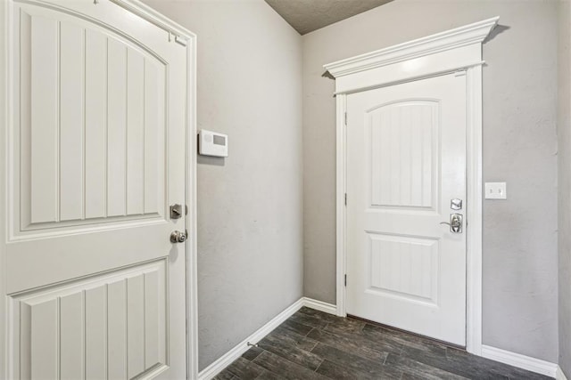 entryway with dark wood-type flooring and baseboards