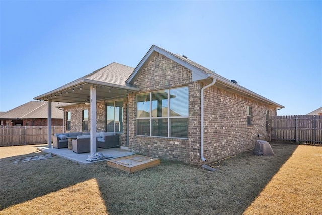 back of property with a fenced backyard, a yard, outdoor lounge area, brick siding, and a patio area