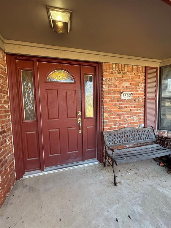 doorway to property featuring brick siding and covered porch