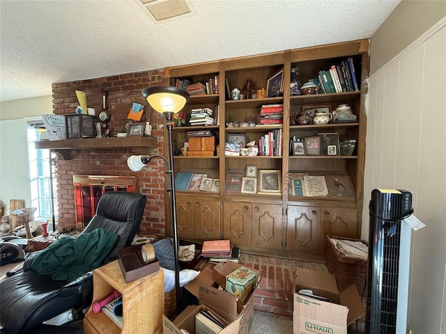 home office with visible vents, a textured ceiling, a fireplace, and a decorative wall