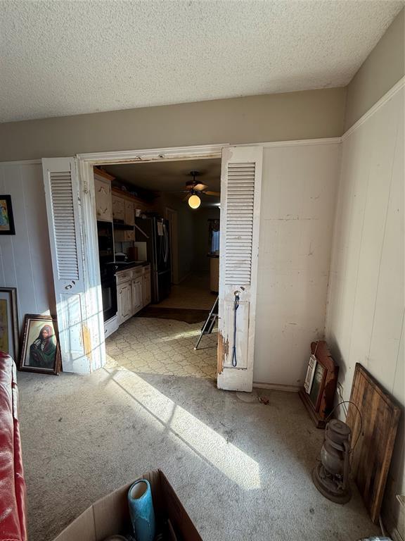 unfurnished living room with ceiling fan and a textured ceiling