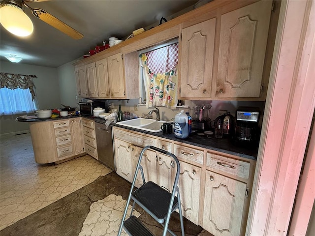 kitchen with a sink, dark countertops, stainless steel dishwasher, a peninsula, and light floors