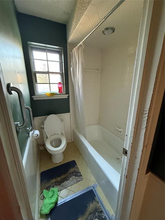 bathroom with tile patterned floors, shower / bathtub combination with curtain, toilet, and a textured ceiling