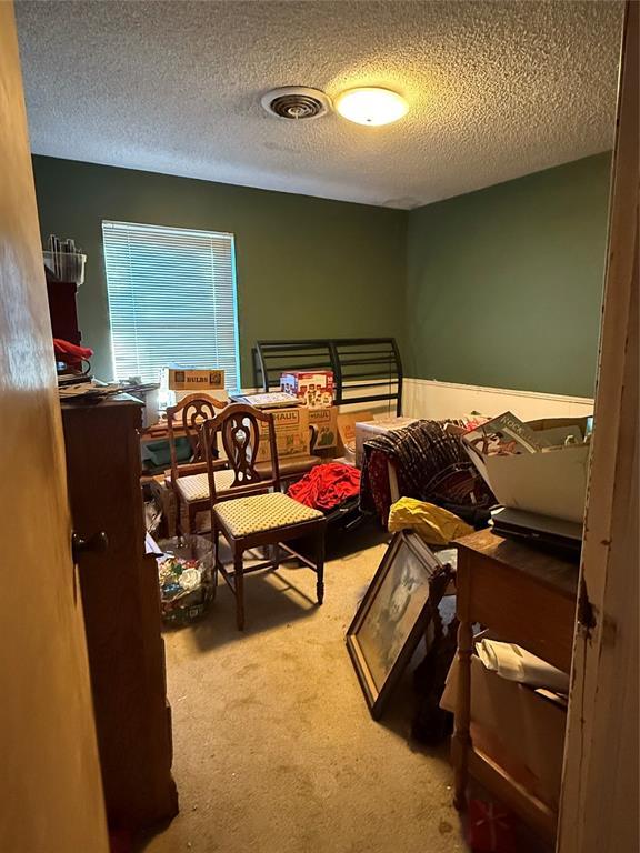 carpeted bedroom with visible vents and a textured ceiling