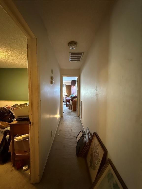 corridor with carpet flooring, visible vents, and a textured ceiling