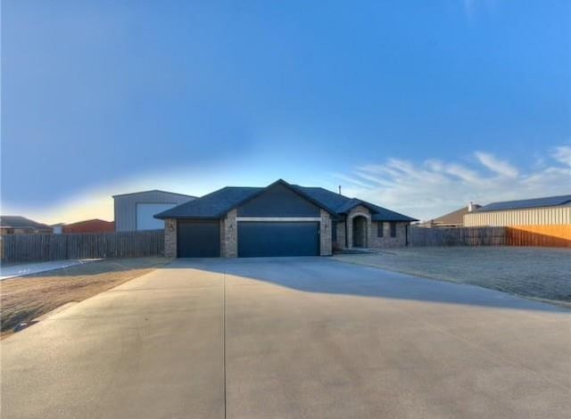 view of front of property with stone siding, concrete driveway, an attached garage, and fence