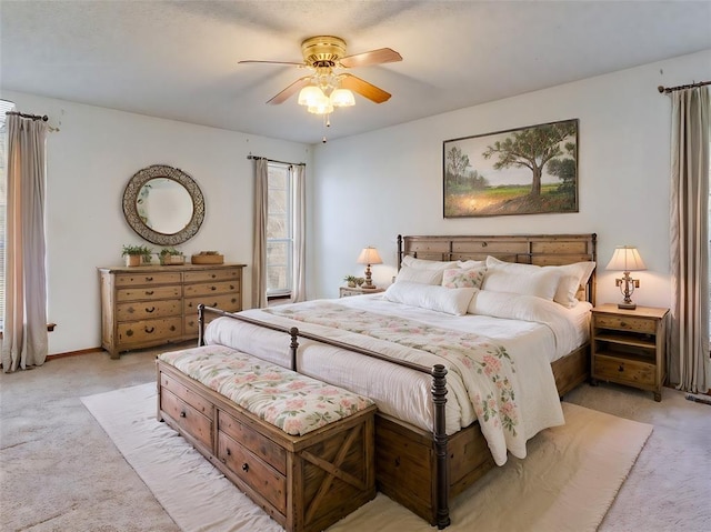 bedroom featuring baseboards, light colored carpet, and a ceiling fan