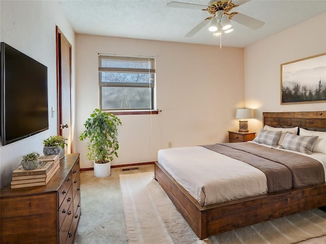 bedroom with visible vents, light carpet, a textured ceiling, baseboards, and ceiling fan