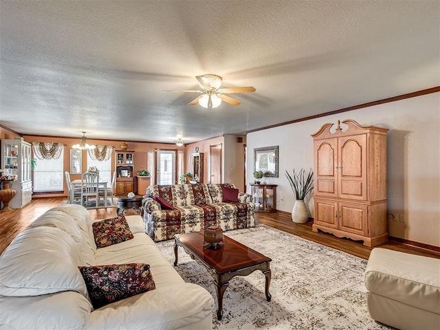 living room with baseboards, a textured ceiling, wood finished floors, and ceiling fan with notable chandelier