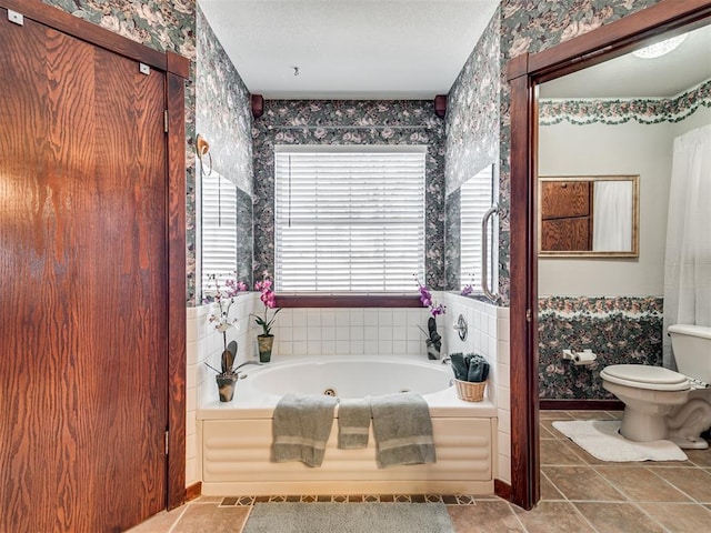 bathroom featuring tile patterned floors, toilet, a textured ceiling, a jetted tub, and wallpapered walls