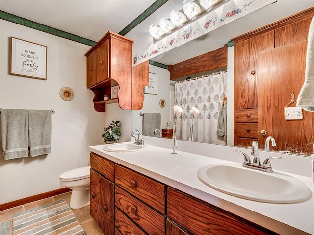 bathroom with double vanity, toilet, baseboards, and a sink