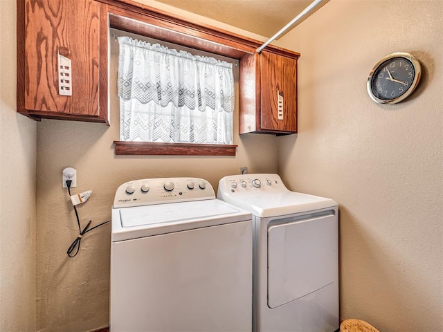 washroom featuring cabinet space, independent washer and dryer, and a textured wall