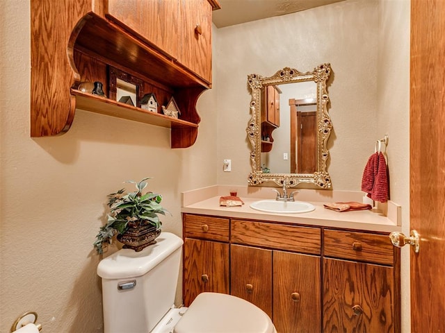 bathroom featuring toilet, vanity, and a textured wall