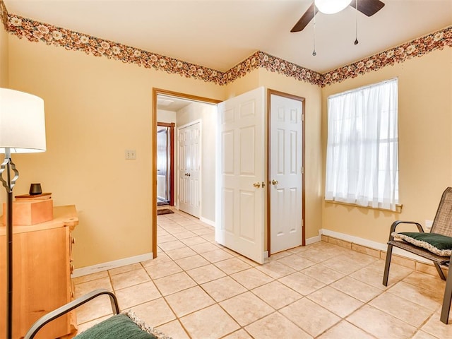 living area featuring light tile patterned floors, baseboards, and a ceiling fan