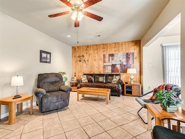 living area with ceiling fan, visible vents, wood walls, and light tile patterned flooring