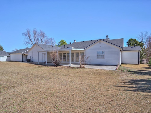 view of front of property with a front yard, a patio area, and a chimney