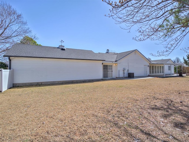 back of house with a shingled roof, fence, a lawn, cooling unit, and a patio area