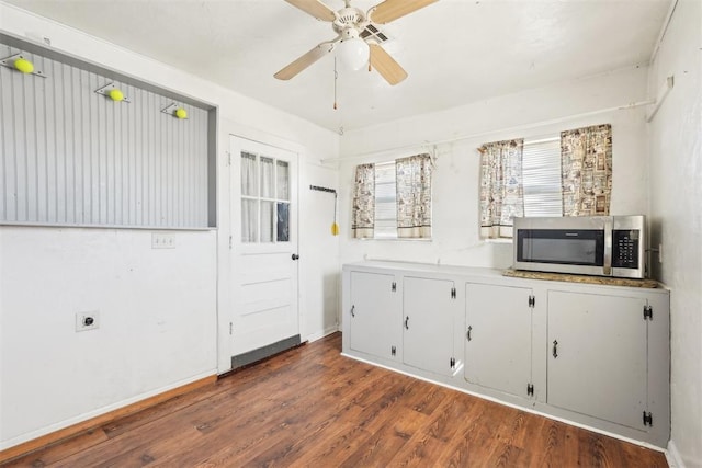 interior space featuring stainless steel microwave, wood finished floors, white cabinetry, light countertops, and ceiling fan