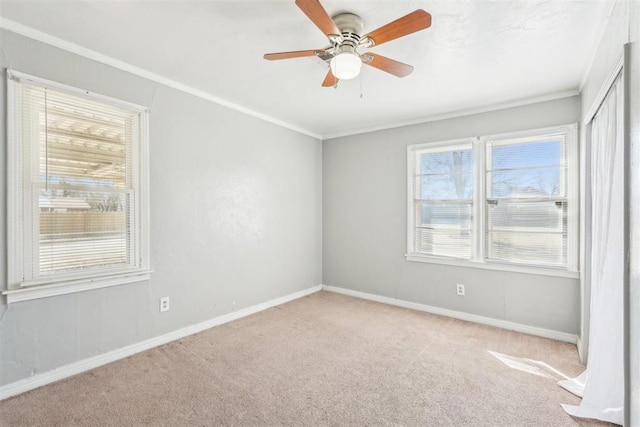 carpeted empty room with ceiling fan, baseboards, and ornamental molding