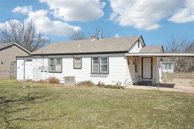 view of front of home with a front lawn, cooling unit, roof with shingles, an attached carport, and a chimney