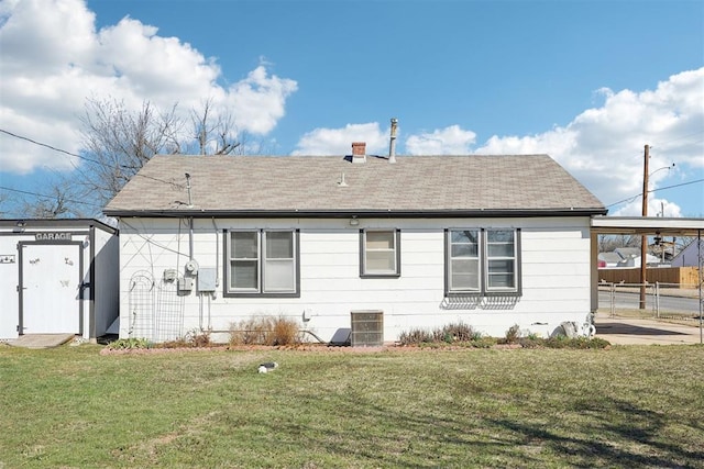 back of house featuring an outbuilding, central AC unit, fence, a yard, and a carport